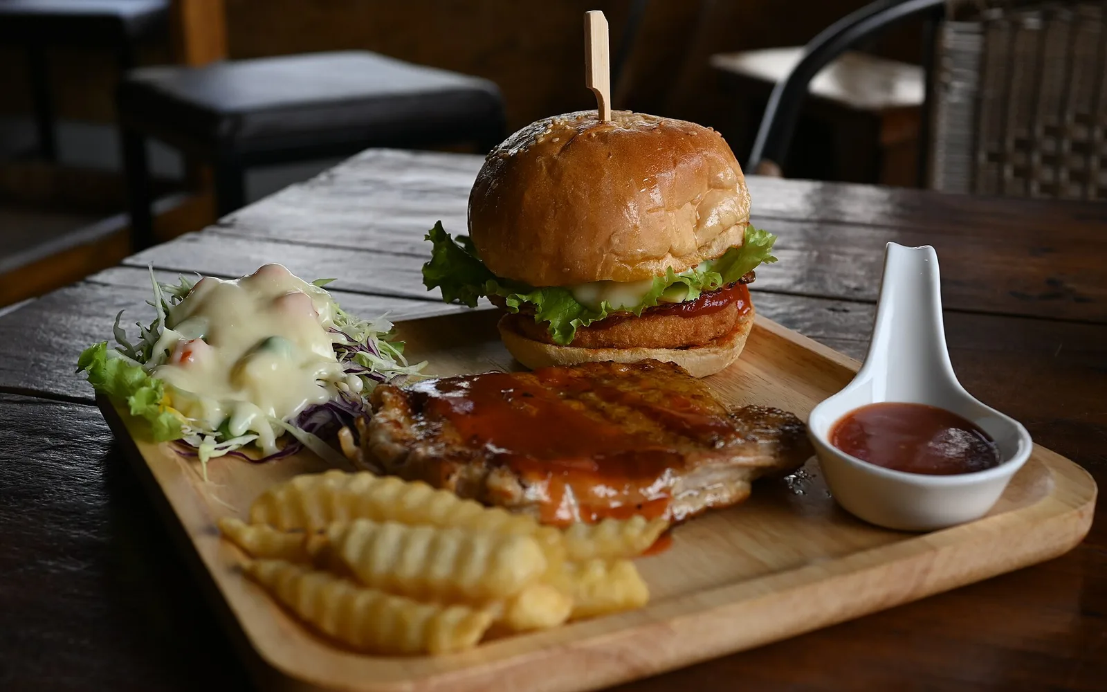 A burger and fries on a wooden board.
