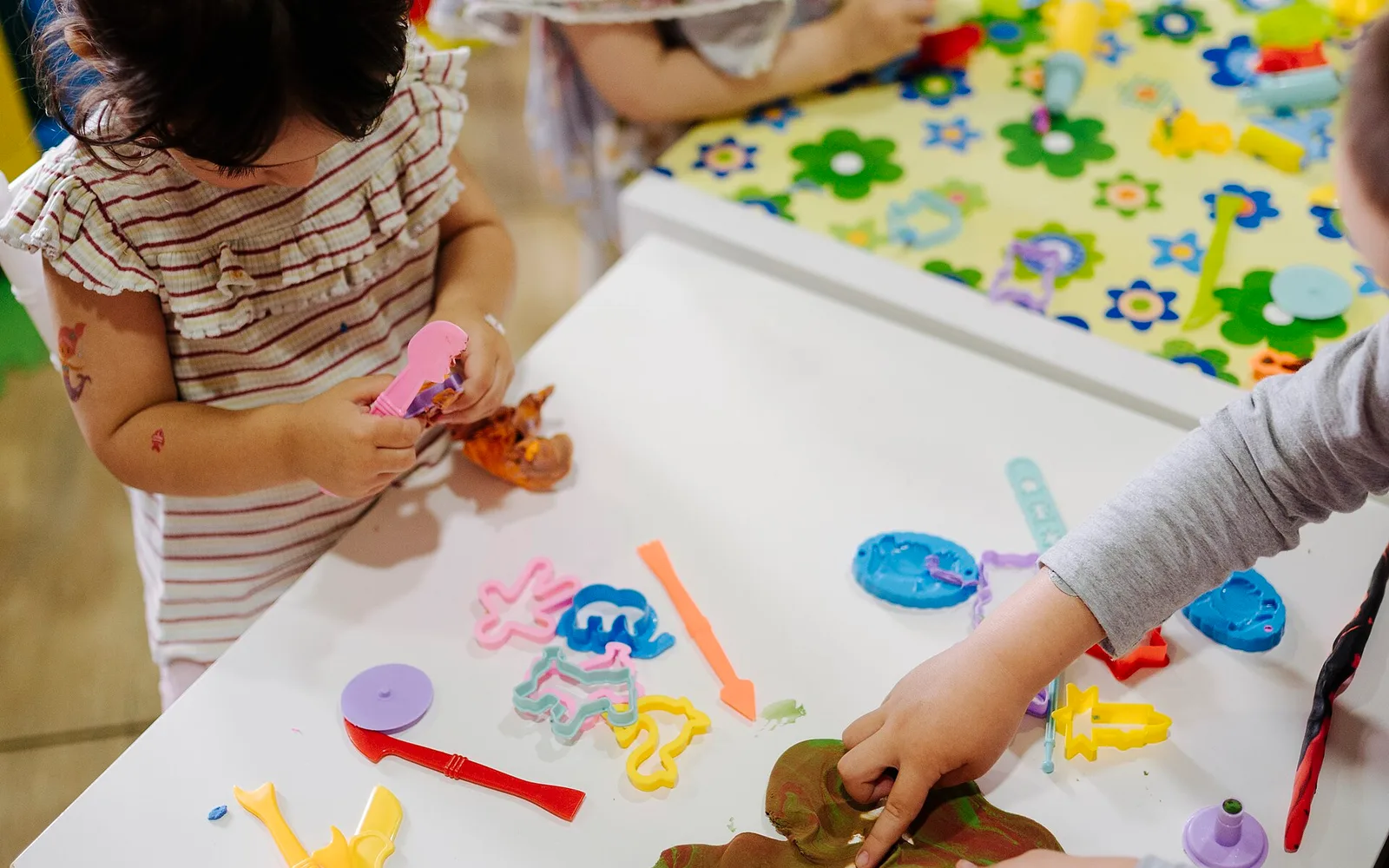 Children playing with colourful craft materials in a classroom.